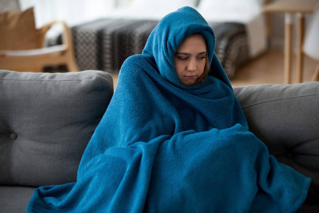 woman covered with warm blue blanket